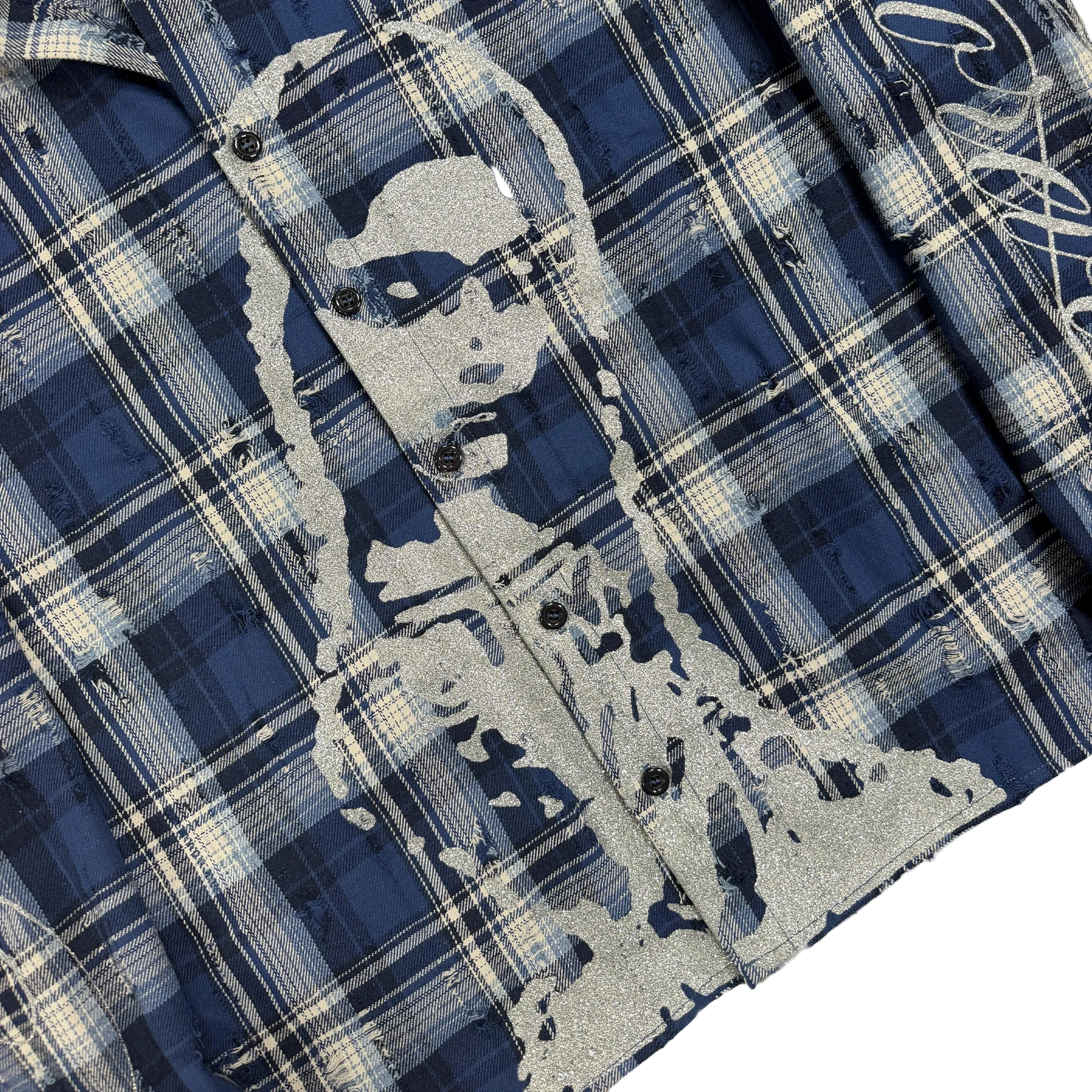 Close-up of a plaid button-front garment in navy, blue, and off-white, with a large distressed gray graphic of a woman's face and hair across the front.